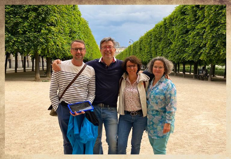 Groupe Famille dans le Jardin du Palais proche des Passages couverts à Paris avec une tablette digitale bleu dans les mains