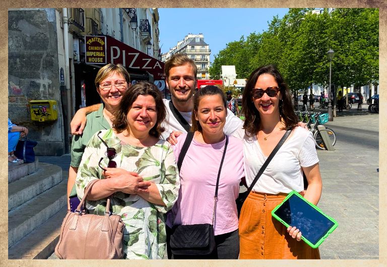 Groupe d'amis avec une tablette digitale verte devant l'Eglise Saint Paul dans le Marais à Paris