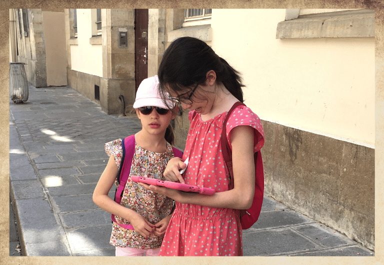 Duo de jeunes filles de 8 à 12 ans avec une tablette digital rose dans le quartier du Marais à Paris