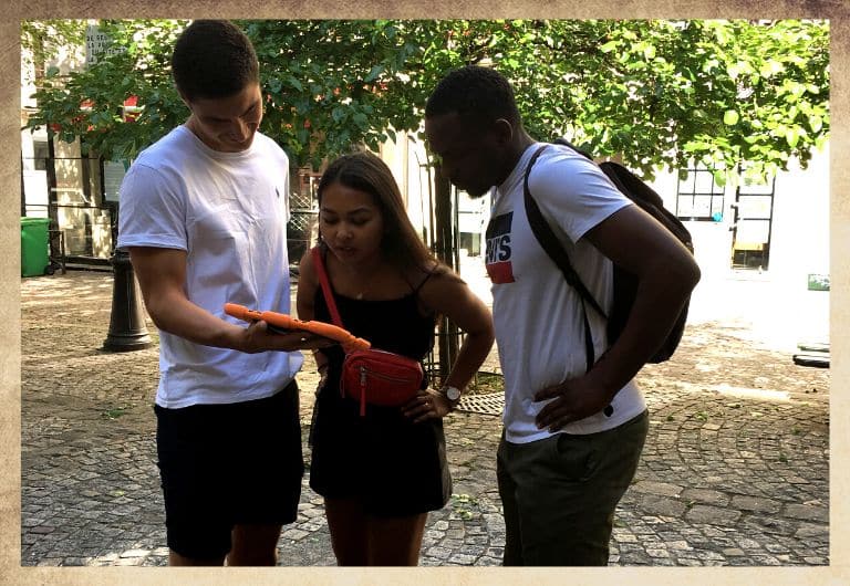 Trio de détective dans les ruelles du Marais à Paris avec une tablette digitale orange