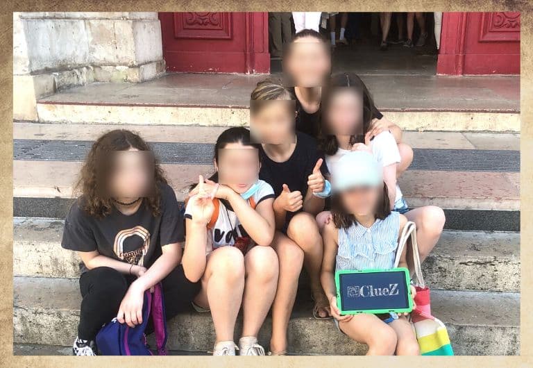 Groupe de jeunes filles dans le Marais devant l'église Saint paul sur les marches, avec une tablette digitale verte